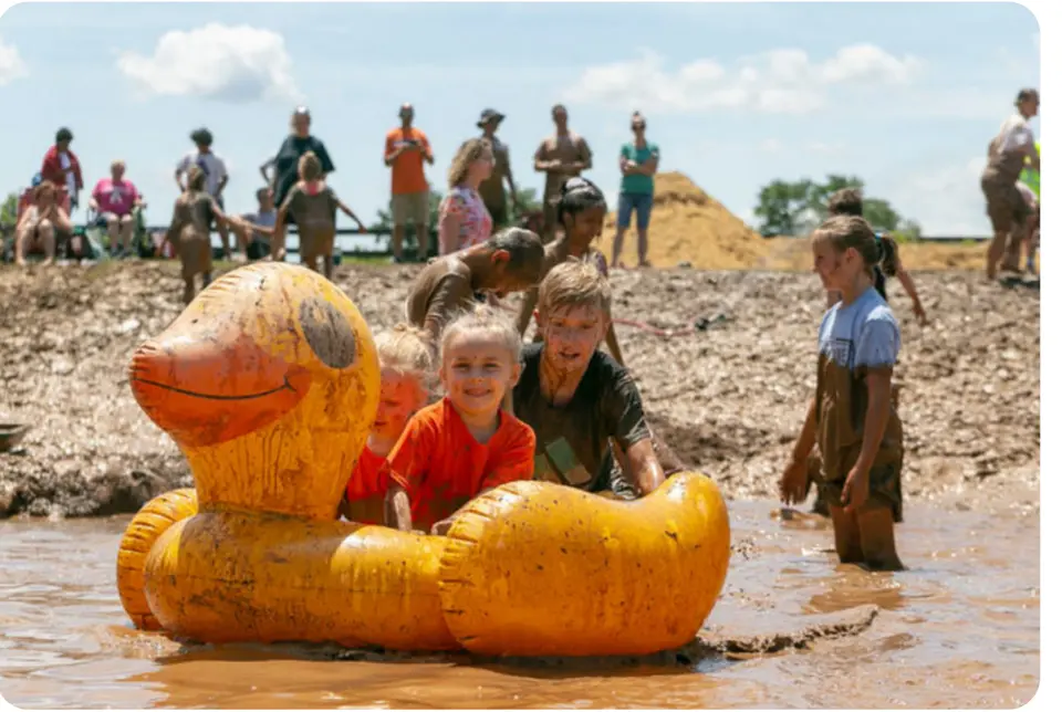 Children play in mud pools with a giant inflatable duck at Montgomery Parks Annual MudFest.
