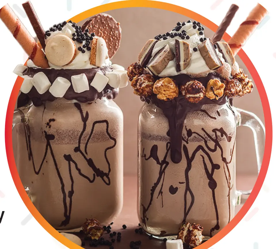 Two over-the-top chocolate milkshakes topped with marshmallows, cookies and wafer rolls. (Bigstock/Alenkasm)