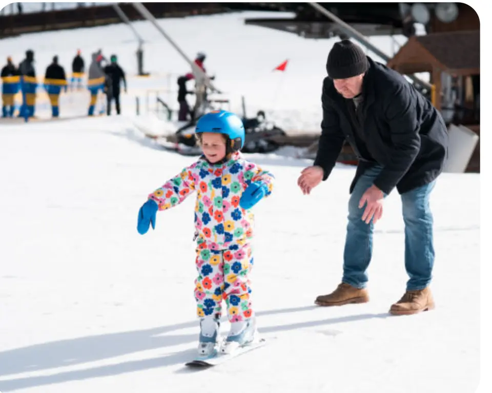 A young skier gets help on the snow.