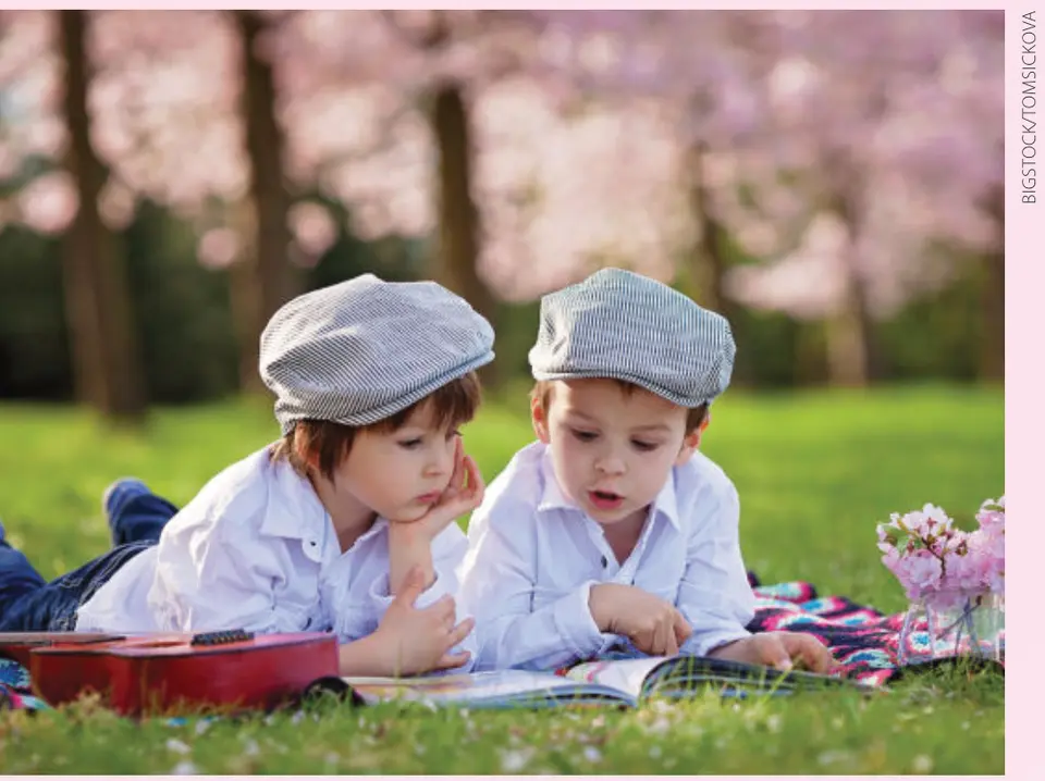Two boys reading outdoors under cherry blossoms. (BIGSTOCK/TOMSICKOVA)