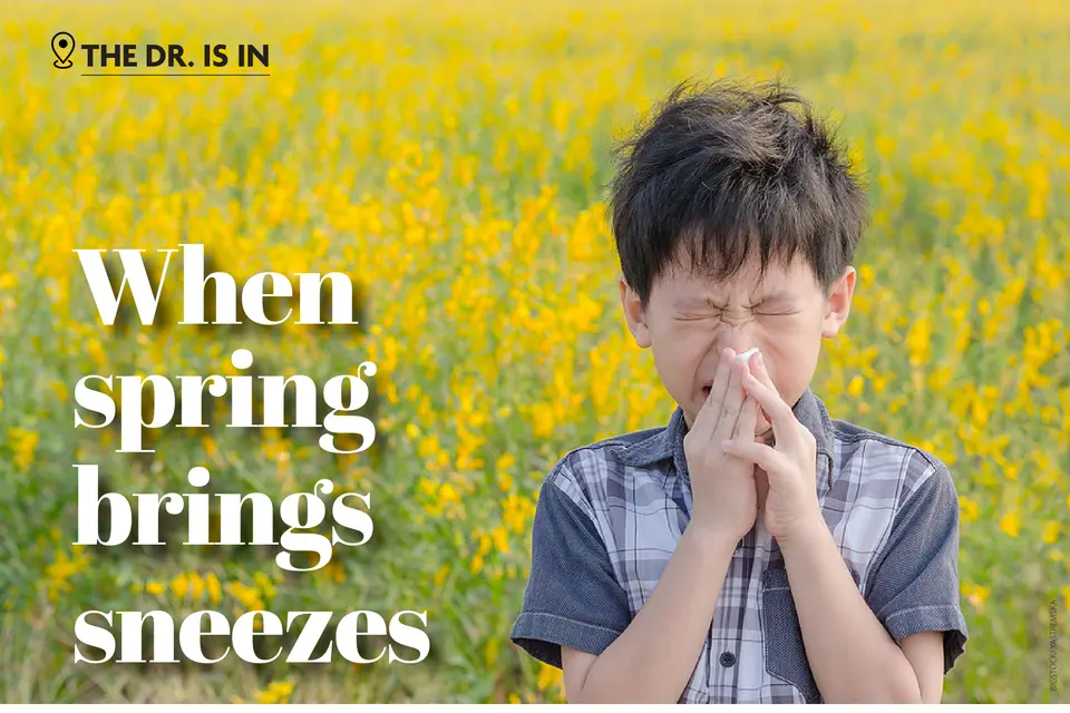 A boy sneezing in a field of yellow flowers. (Bigstock/Yastremska)