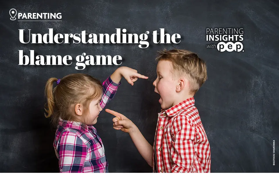 Two children pointing fingers at each other in front of a chalkboard. (Bigstock/Sharomka)