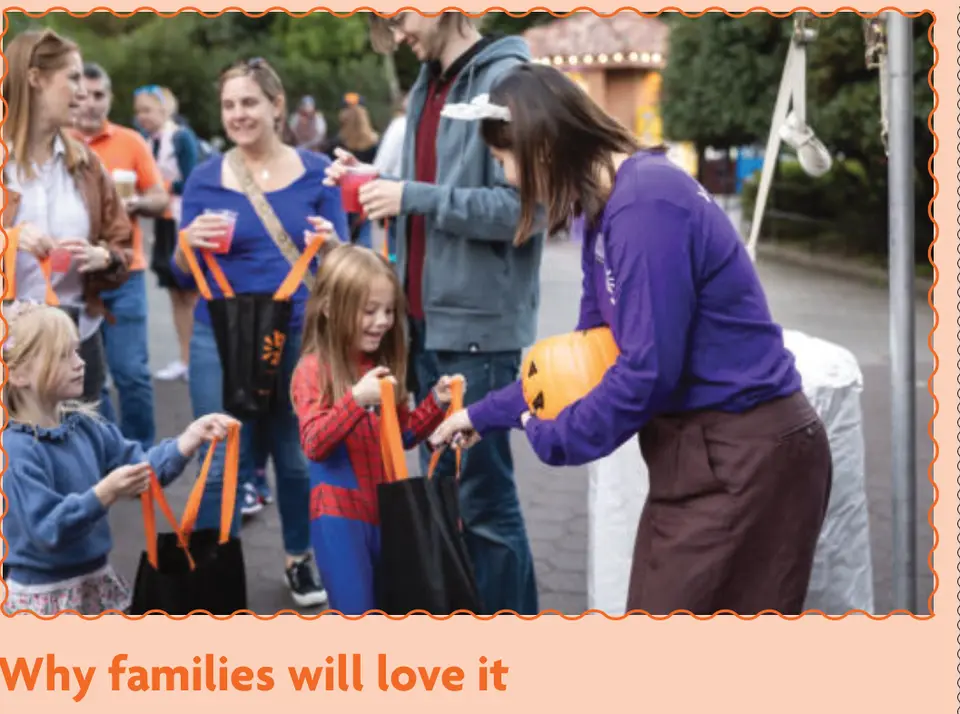 A zoo volunteer passes out treats to young trick-or-treaters.